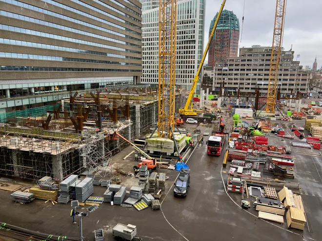 A construction site seen from above, tower cranes and steelwork among office towers on a grey day
