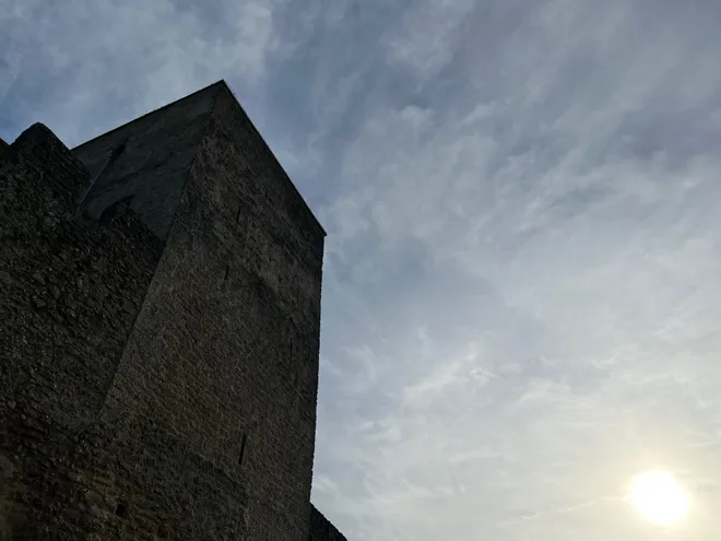 A stone tower of the Hohensalzburg fortress against a bright, hazy sky