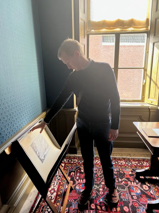 Myself in a wood-panelled room leaning over a framed print on a tilted display stand